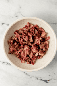 Chopped up ham hocks in white bowl.