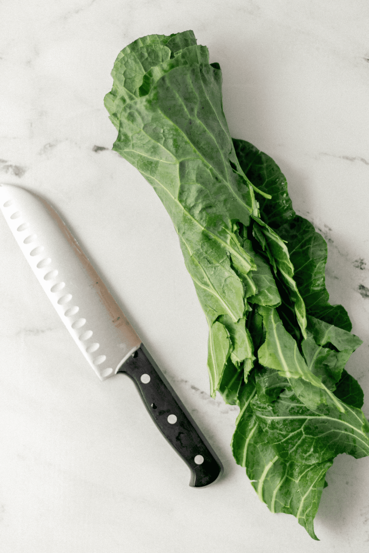 collard greens bunch rolled beside a knife 