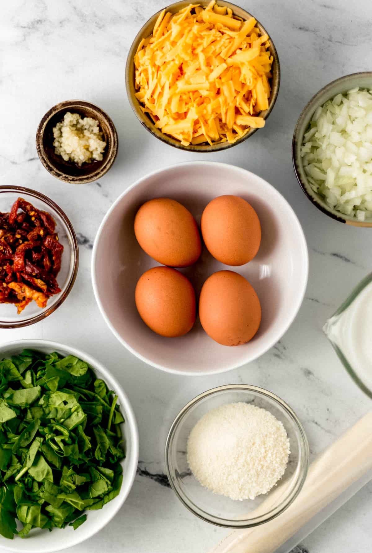 ingredients needed to make quiche in separate bowls and containers 