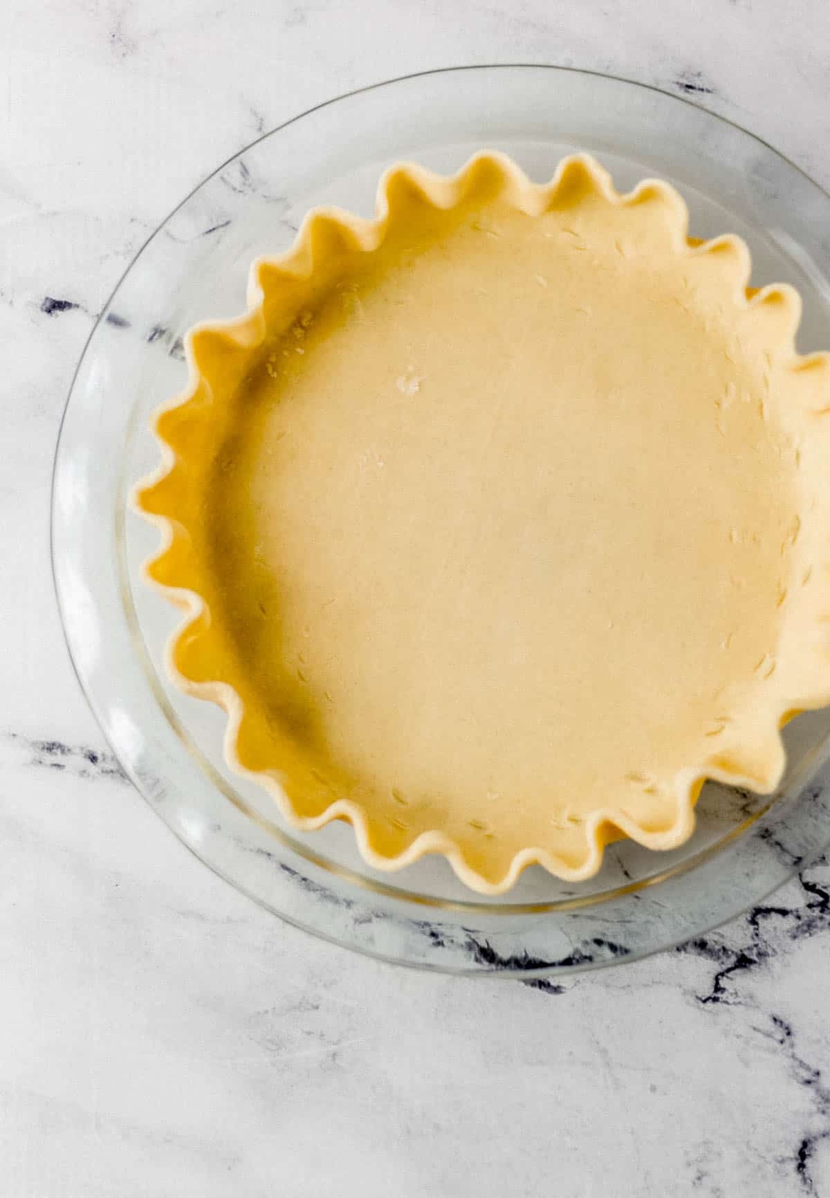 overhead view of pie crust added to glass pie plate 