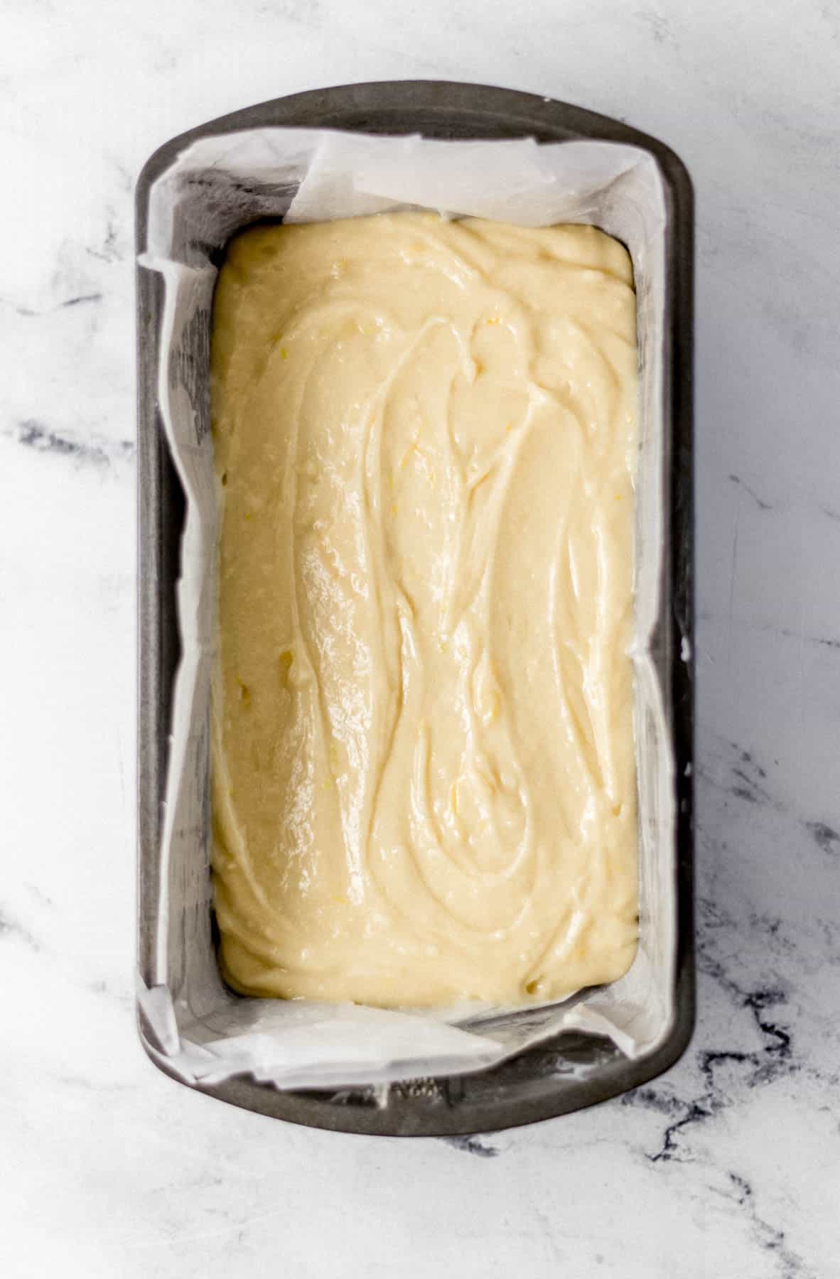 lemon bread mixture added to parchment lined loaf pan 