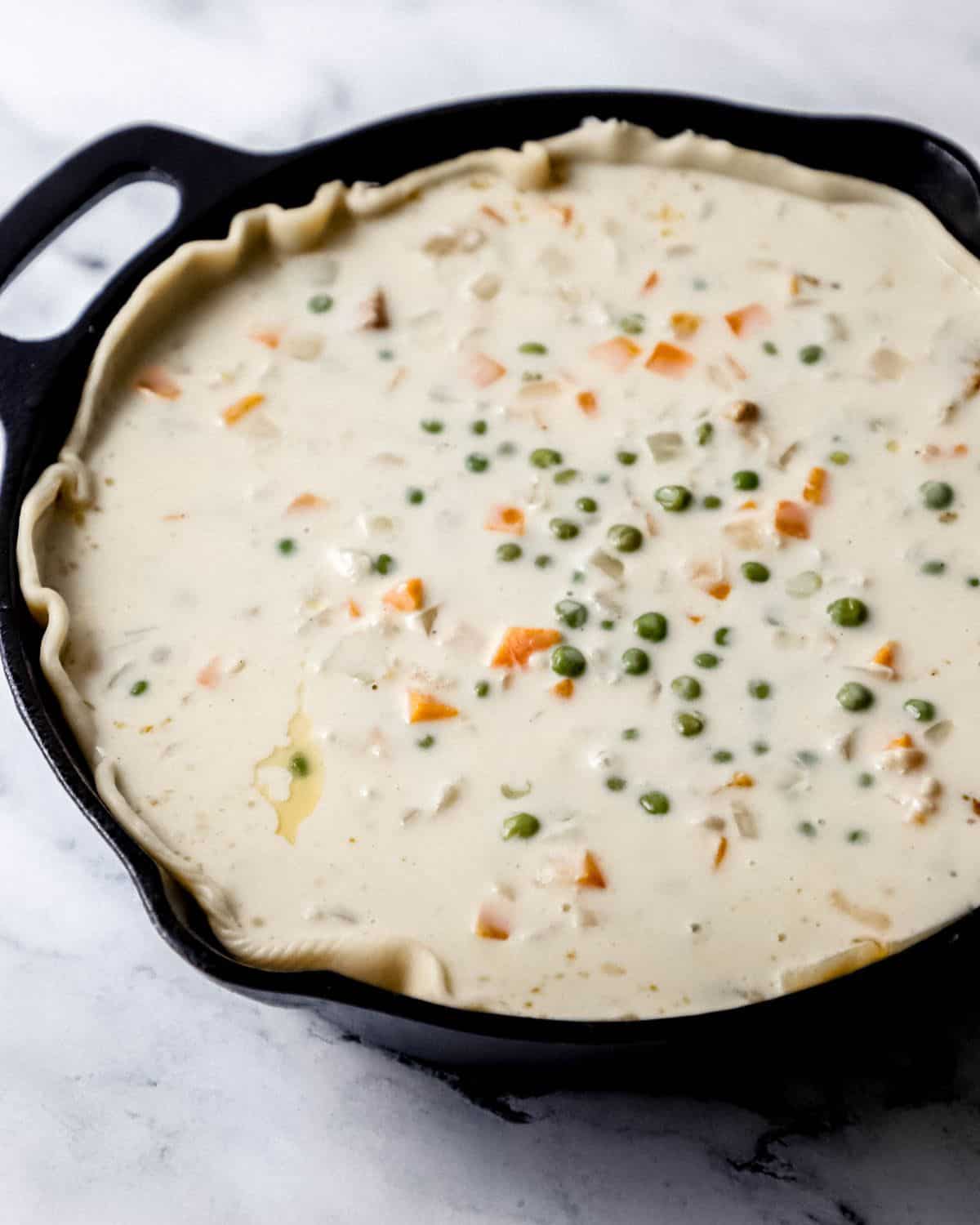 Close up side view of all ingredients for pot pie filling in cast iron skillet. 