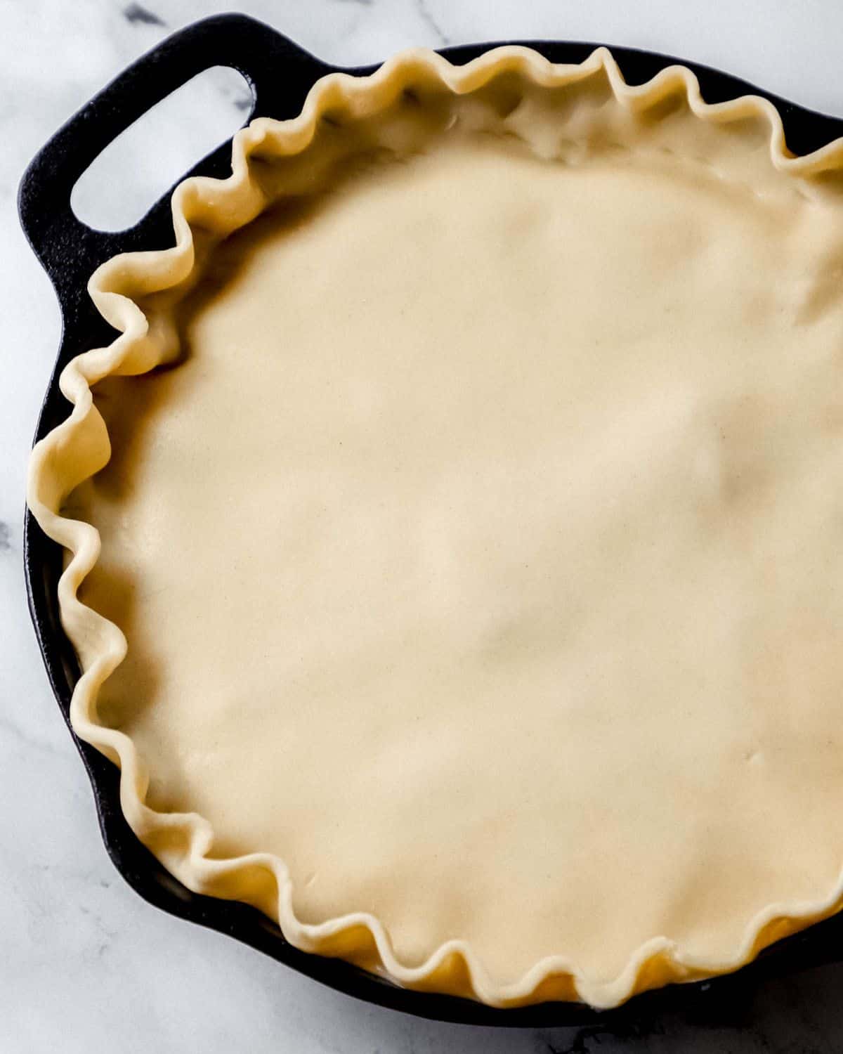 Close up view of chicken pot pie in cast iron skillet before baking. 