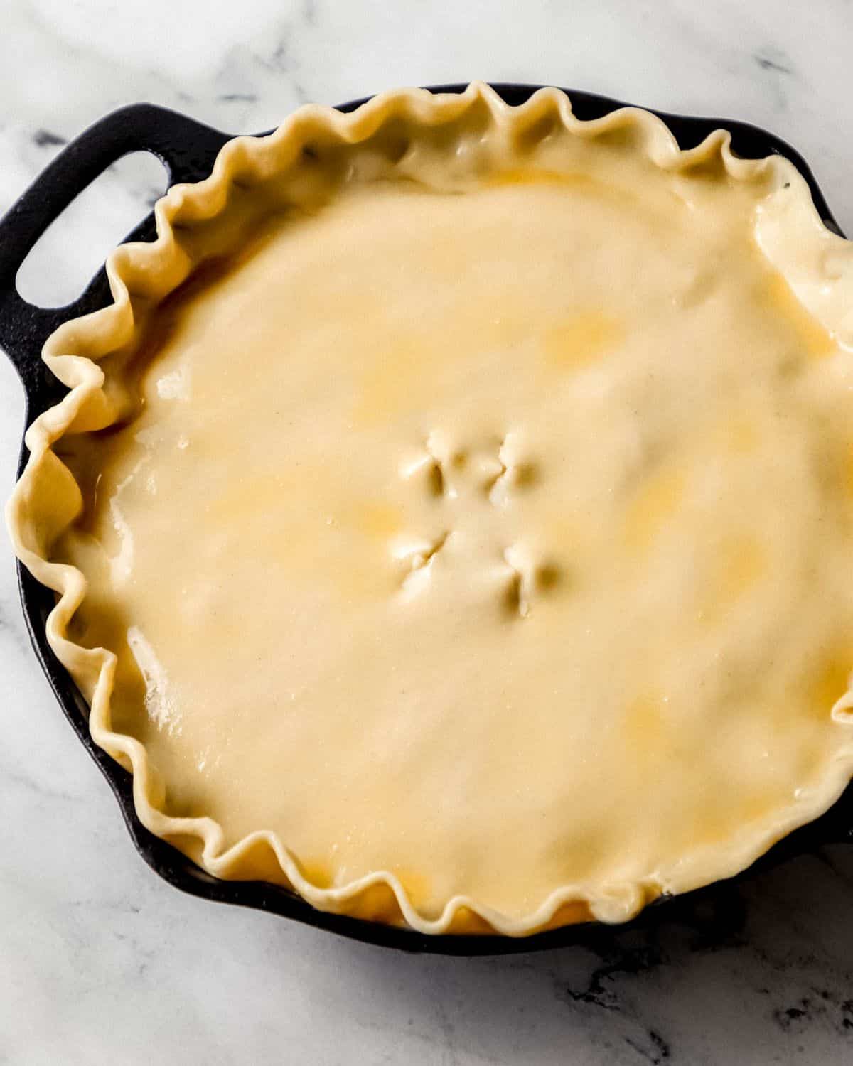 Overhead view of pot pie topped with egg wash before baking. 