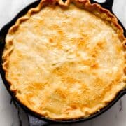 Overhead view of finished pot pie in cast iron skillet on marble surface.