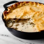 Close up side view of finished pot pie in cast iron skillet with some taken out of it.