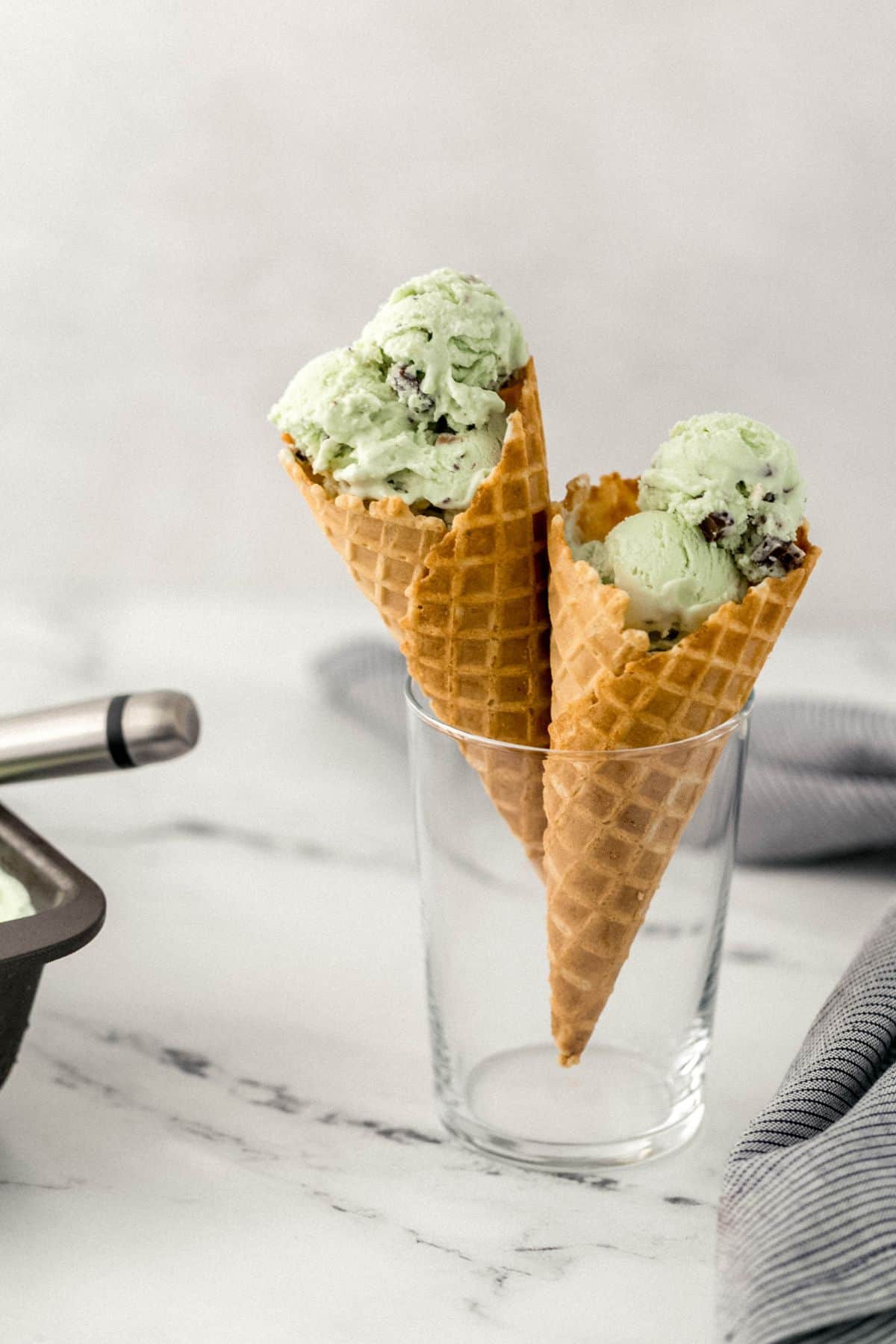 glass with two mint chocolate chip ice cream cones in it 