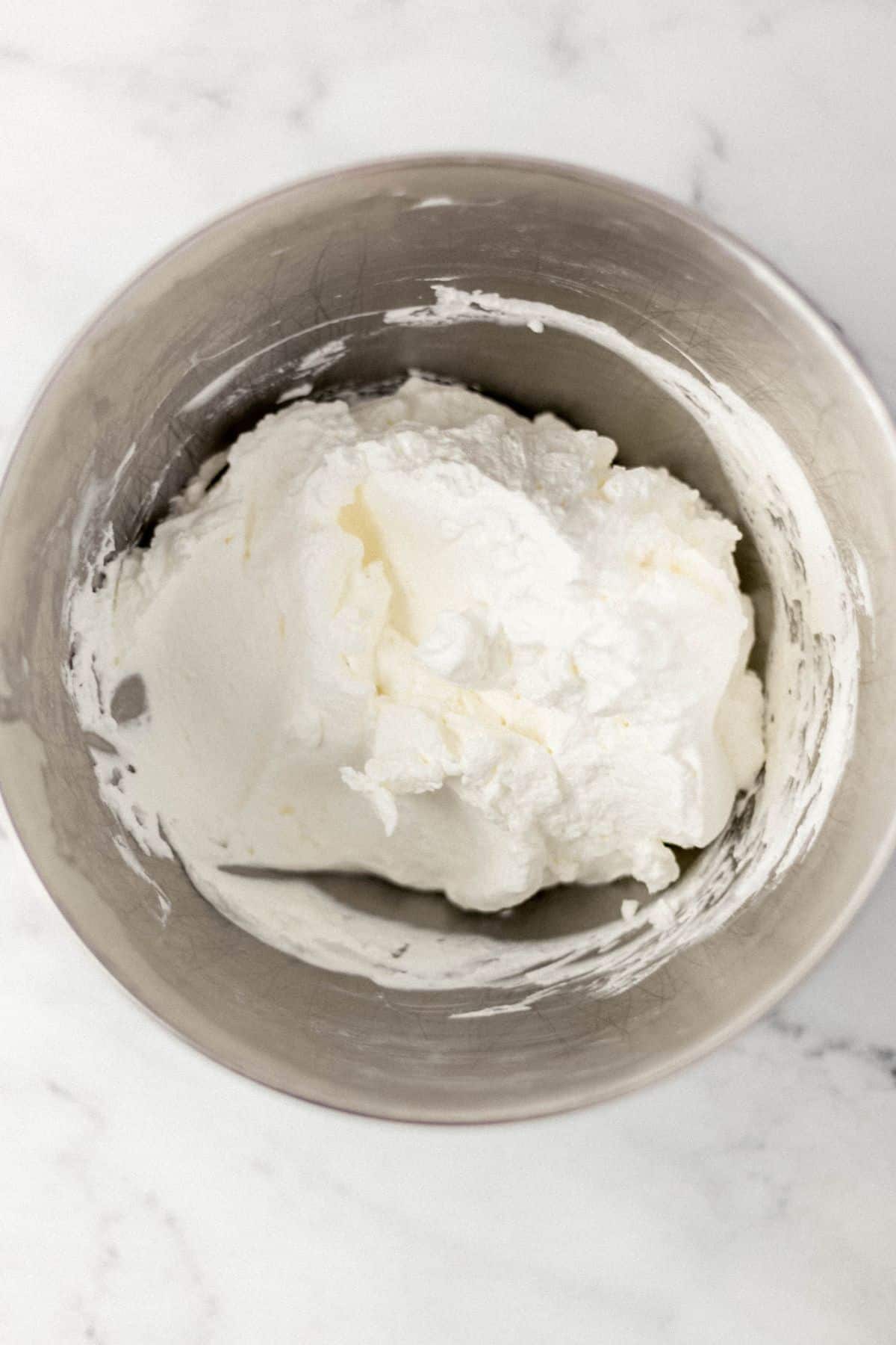 overhead shot of stand mixer bowl with whipped cream in it 