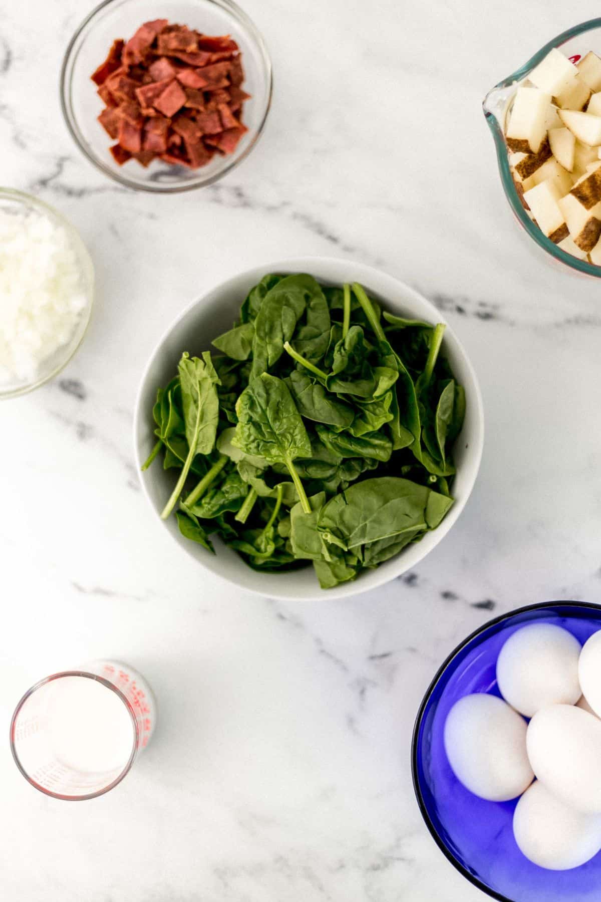 overhead view of ingredients needed to make frittata in separate bowls 