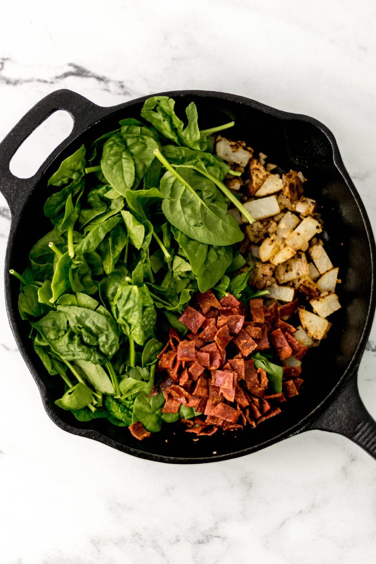 spinach, bacon, and potatoes in cast iron skillet 