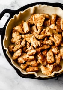 Cooked chicken added to pie crust in cast iron skillet.