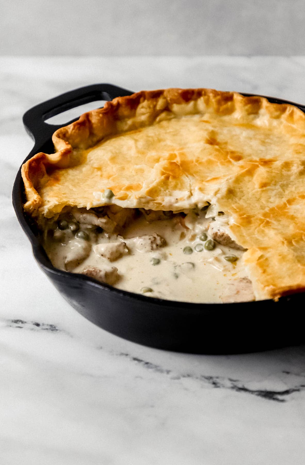 close up side view of pot pie in skillet with pieces cut out of it 