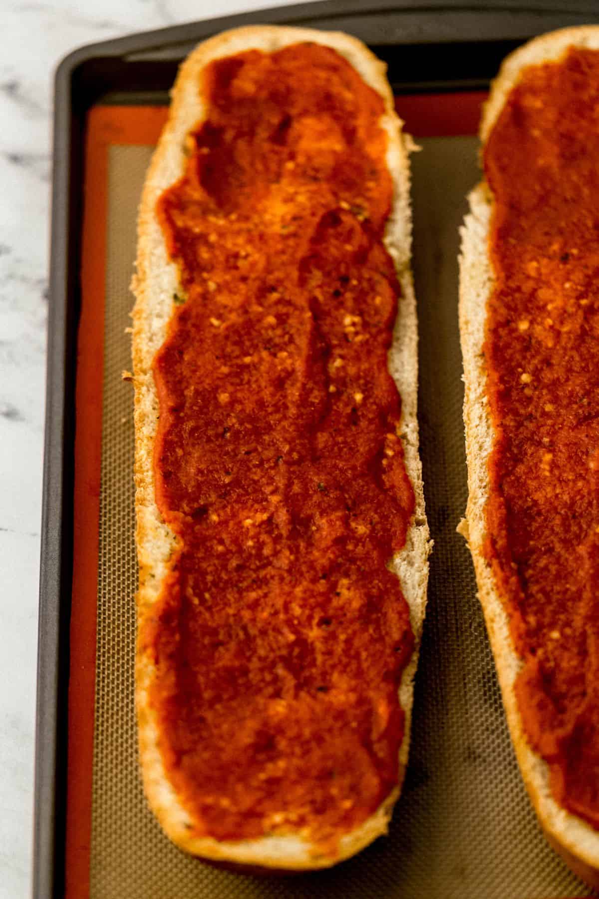 sauce added to bread on baking sheet 