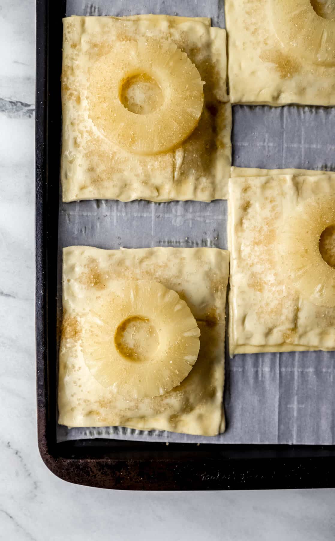 four tarts on parchment lined baking sheet before baking 