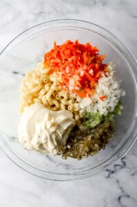 Salad ingredients added to large glass mixing bowl.