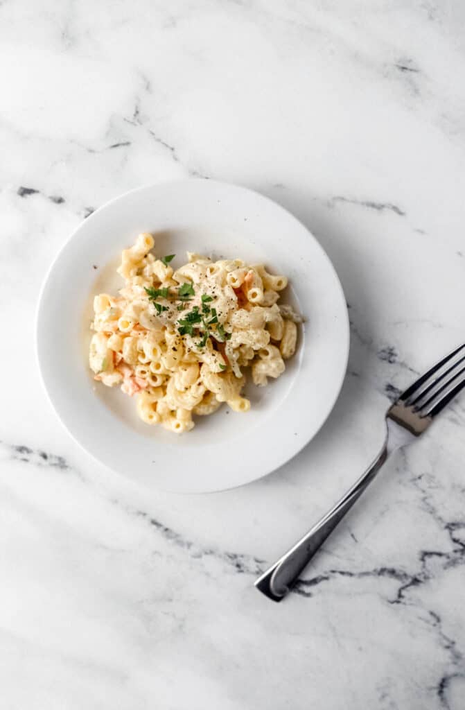 white plate of serving of pasta salad next to a fork