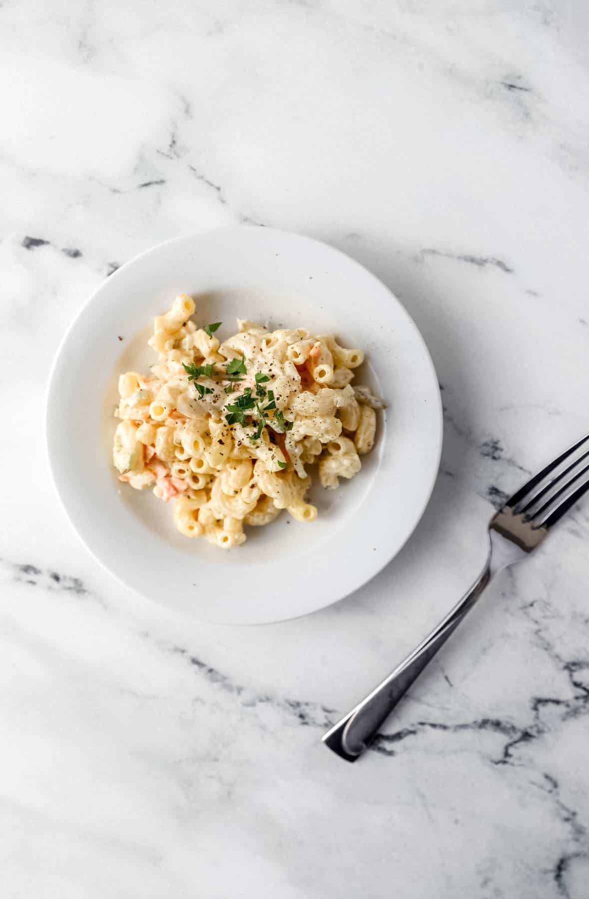 small white plate with pasta salad on it by a fork 