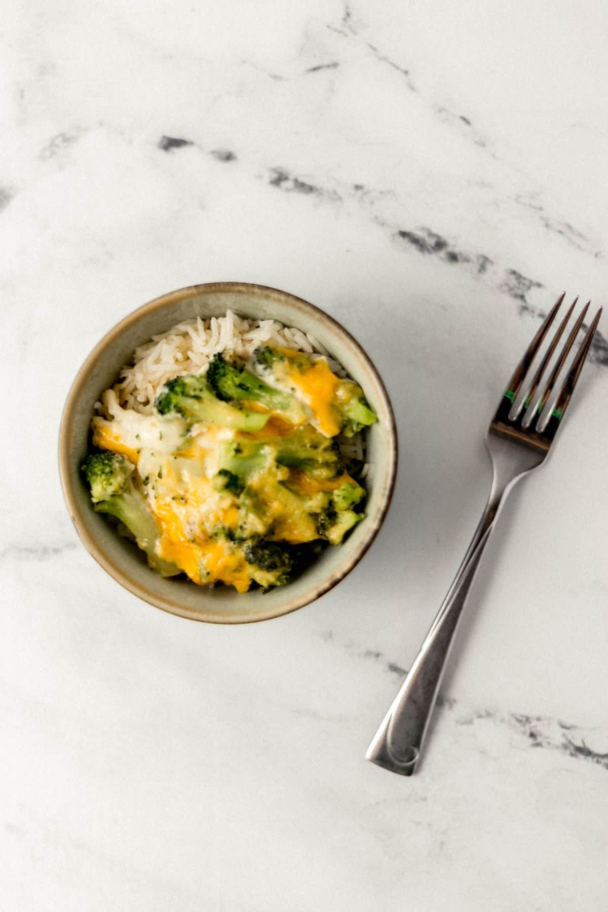 small bowl of chicken and broccoli casserole with rice beside a fork 