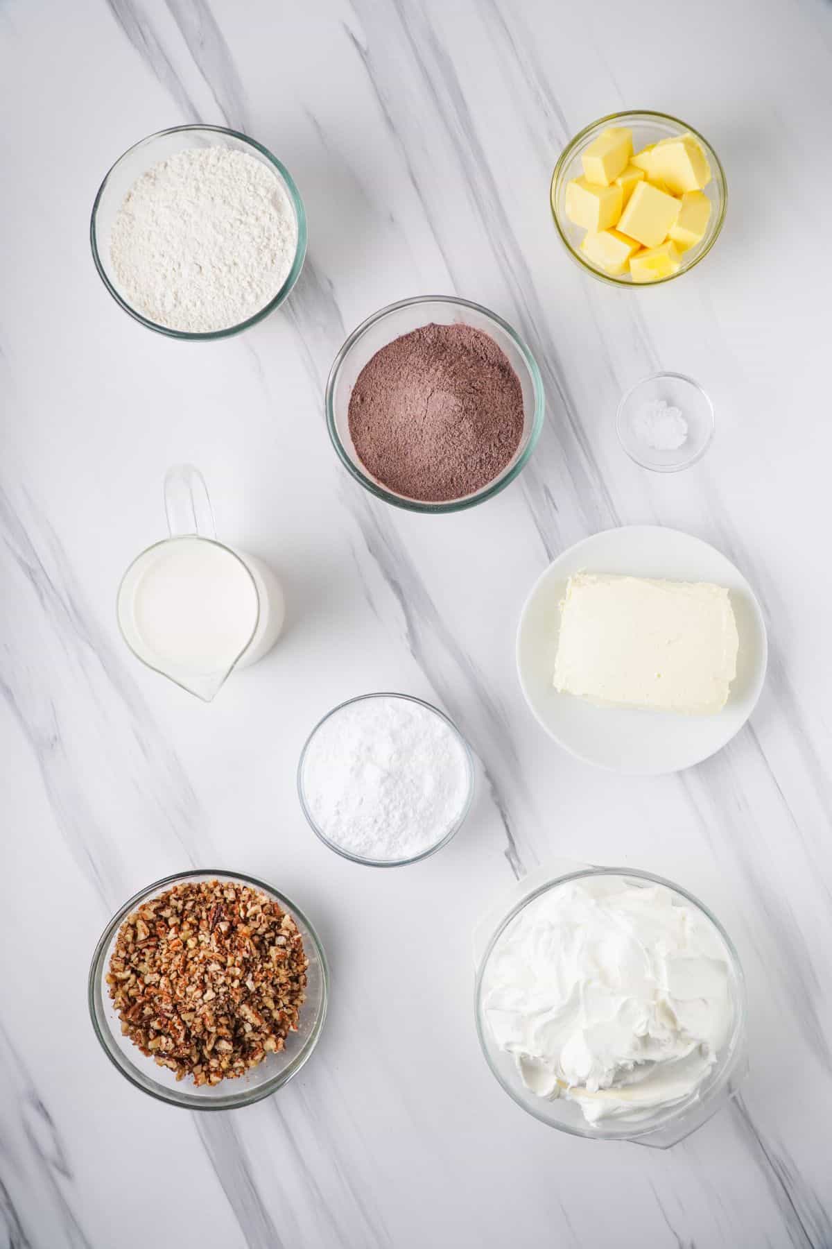 overhead view of ingredients needed to make chocolate delight in separate bowls on marble surface 