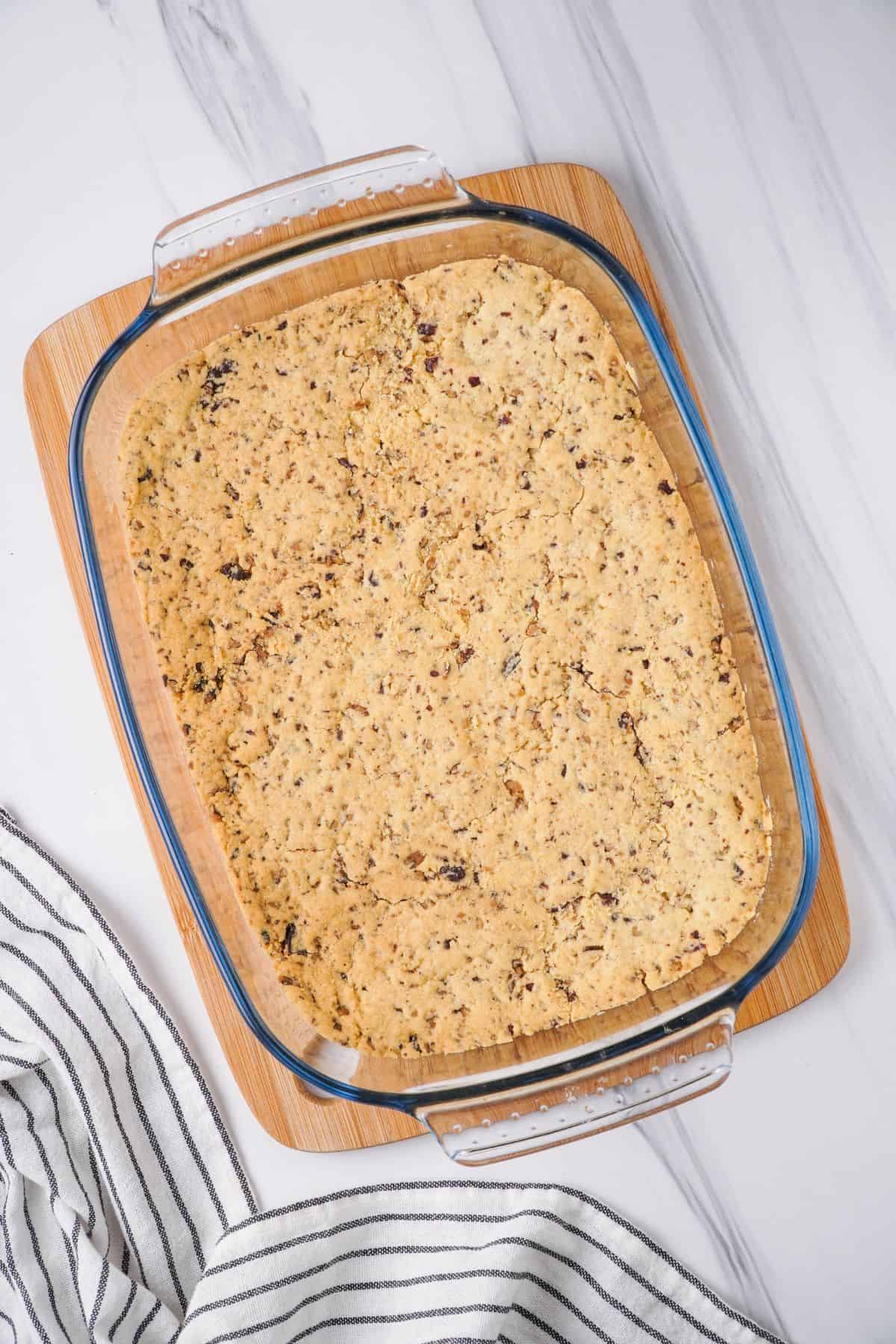 Overhead view of baked crust in rectangle glass baking dish on top of wooden cutting board. 