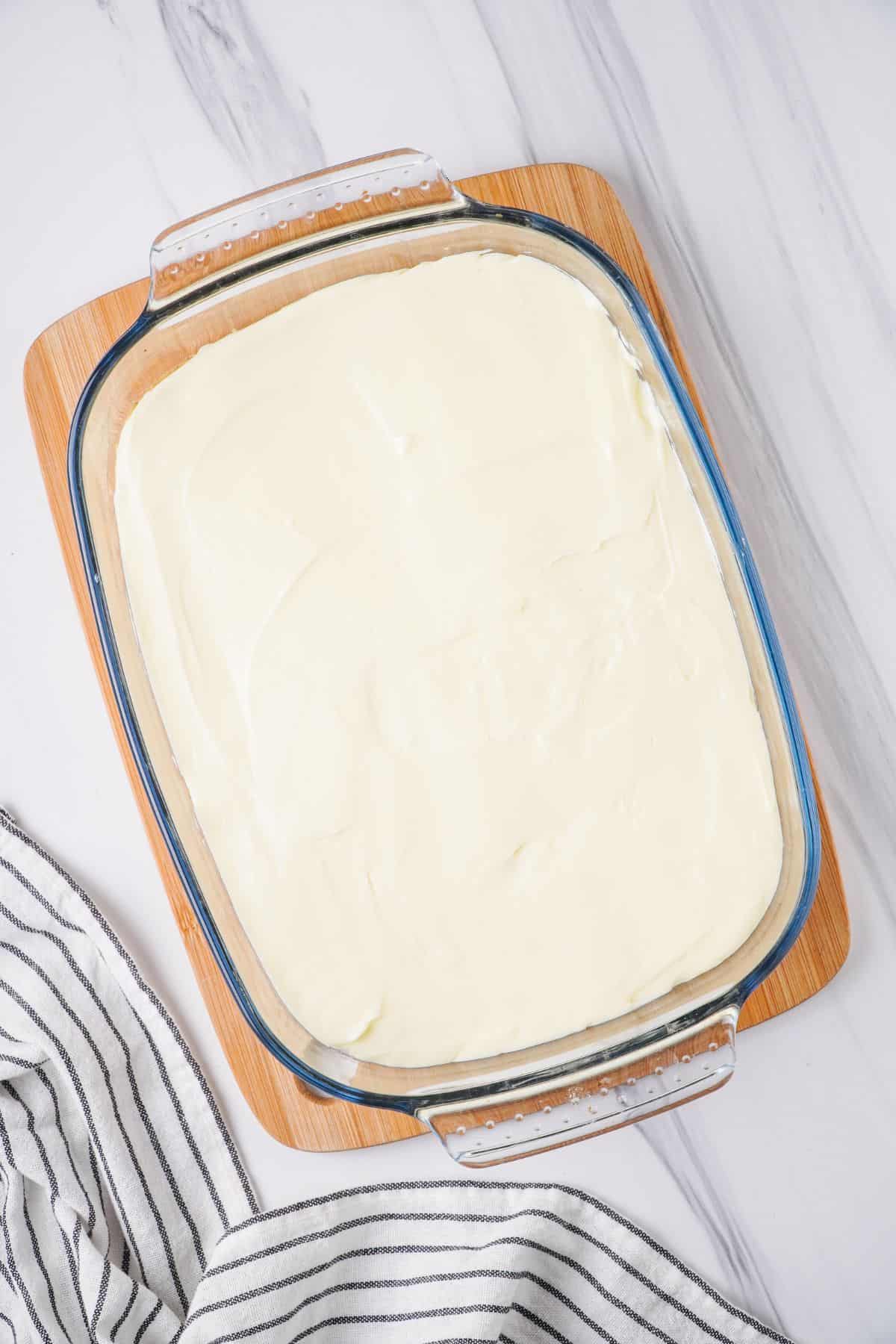 Cream Cheese layer added to glass baking dish on top of crust. 