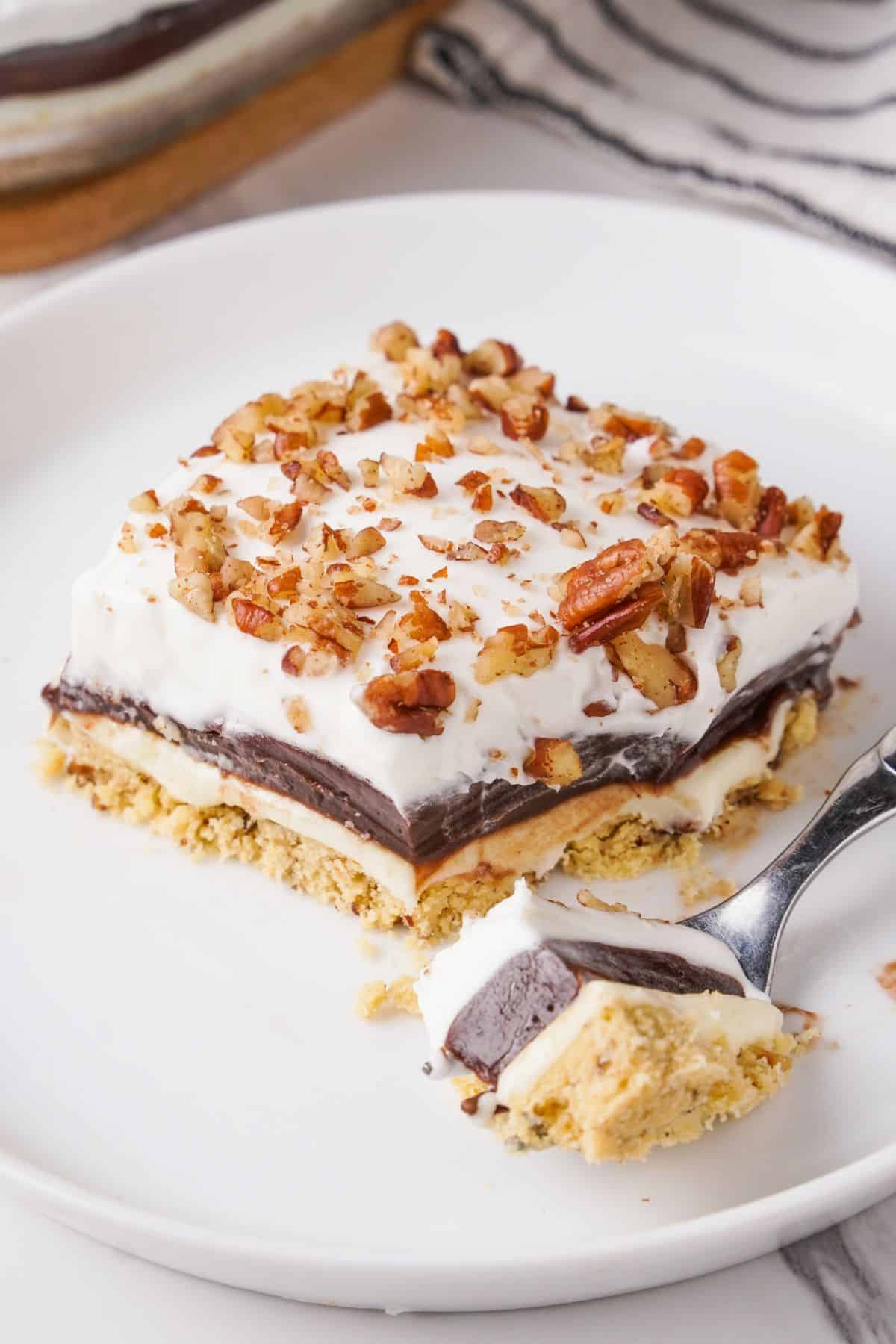 Close up view of piece of dessert on white plate with a fork in it. 