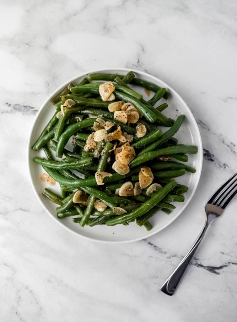 overhead view of green beans on white plate