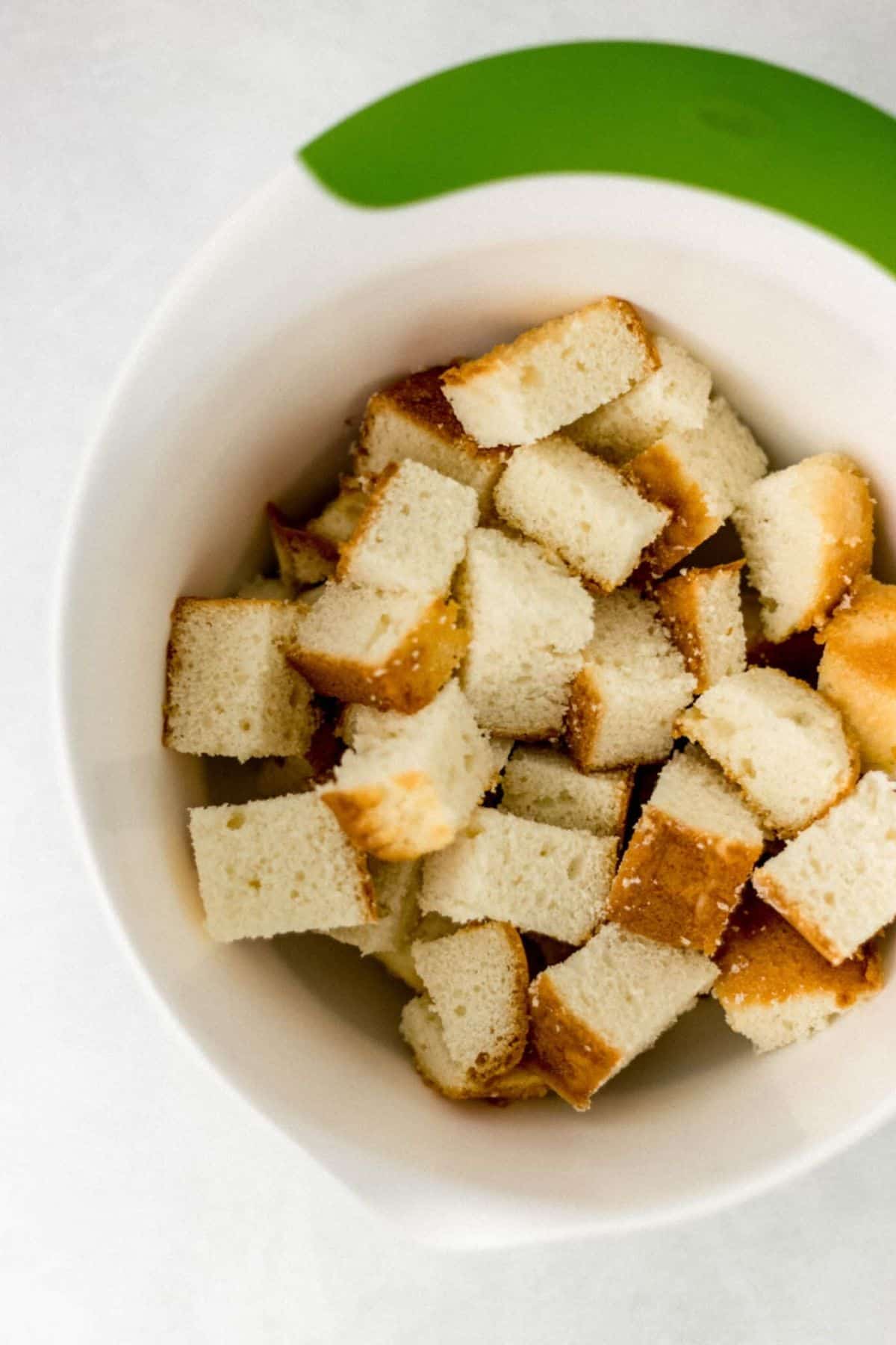 overhead view of white bowl with cut up cake in it