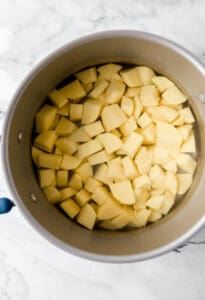 Overhead view of cut potato in large pot.