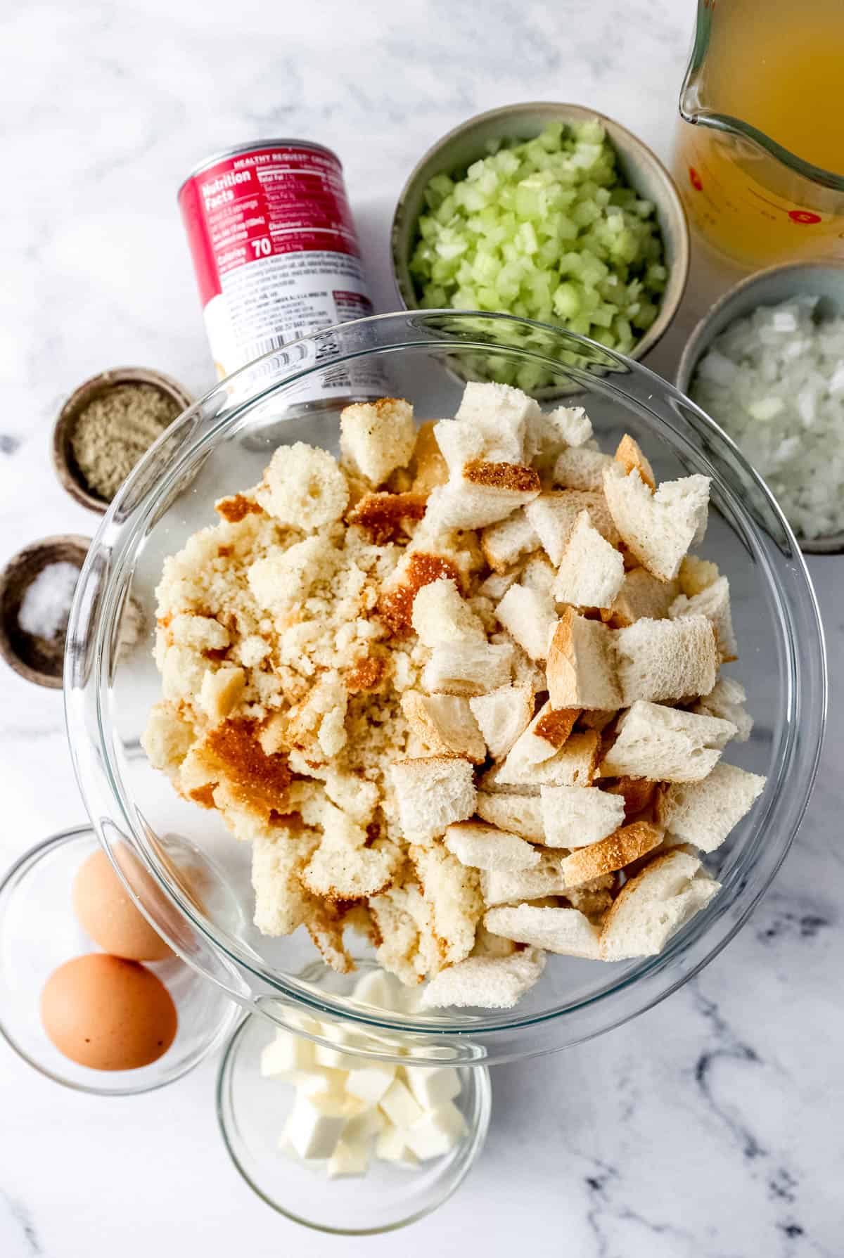 Ingredients needed to make dressing in separate bowls and containers on marble surface. 