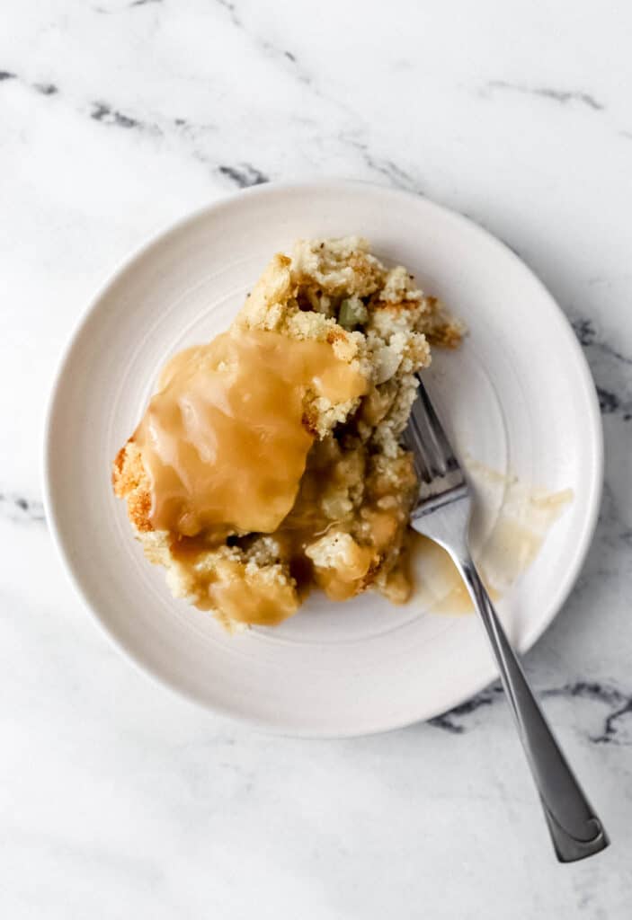 Plate of dressing topped with gravy with a fork on it.