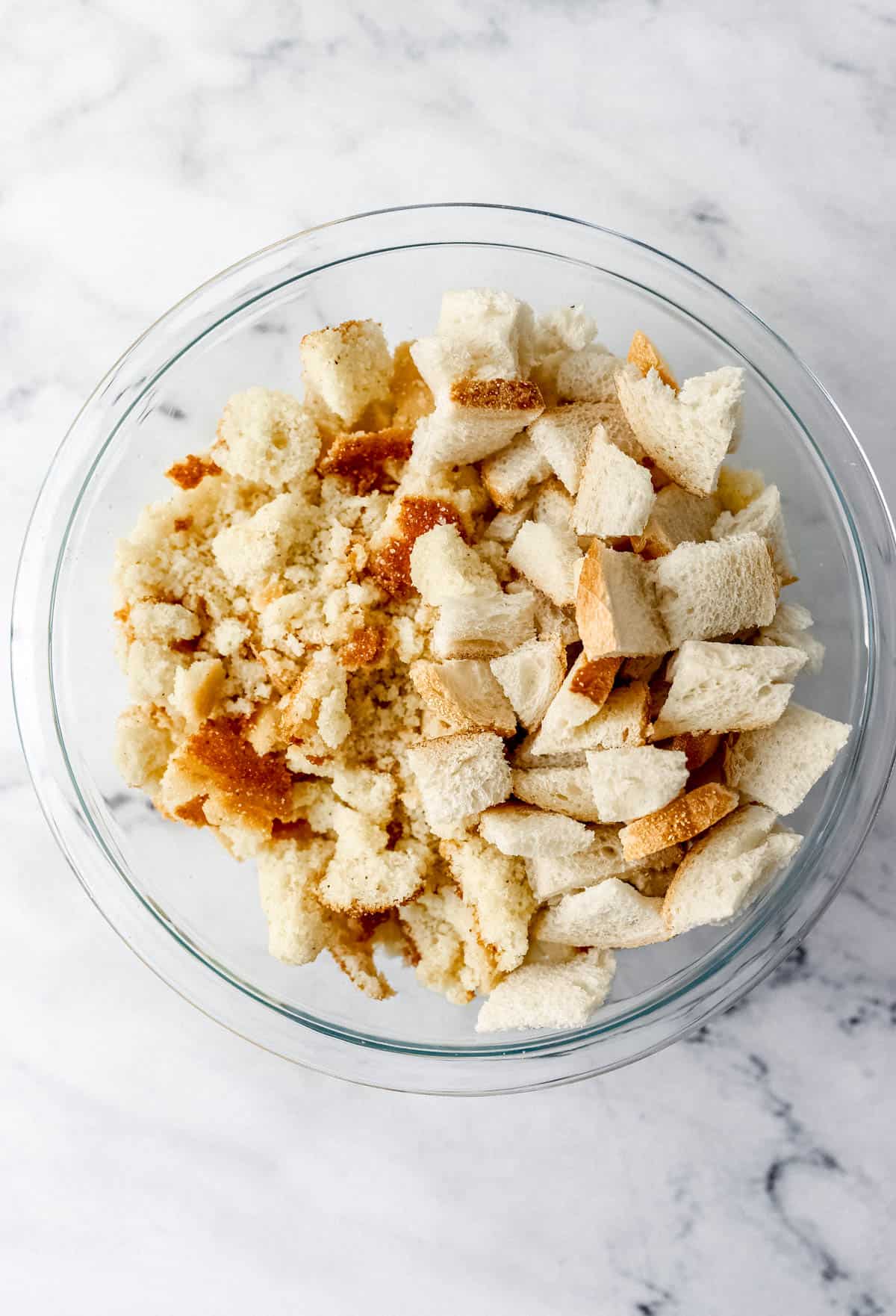 Crumbled cornbread and bread in large glass mixing bowl. 