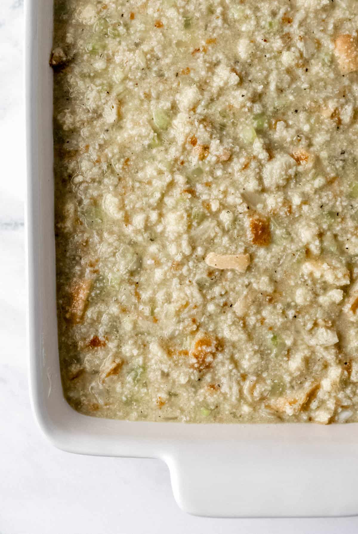 Overhead view of unbaked dressing in white rectangle baking dish. 