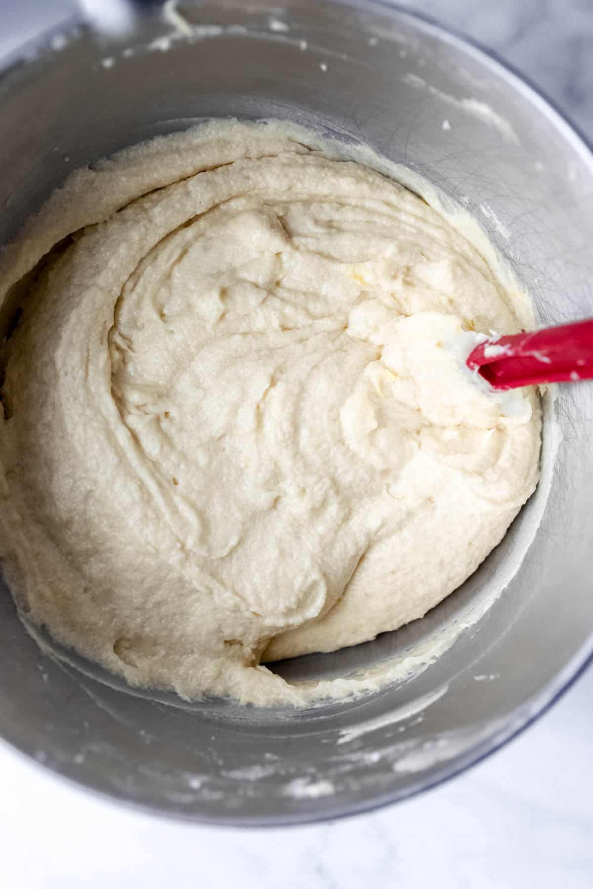 Rum cake batter in stand mixer bowl with rubber spatula.