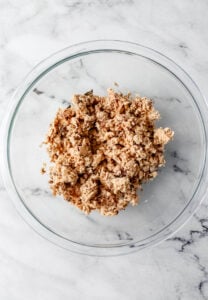 Overhead view of canned salmon added to large glass mixing bowl.
