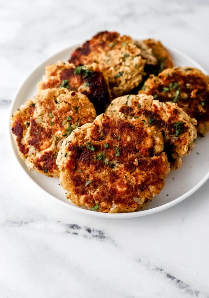 Close up view of finished salmon patties on white plate.