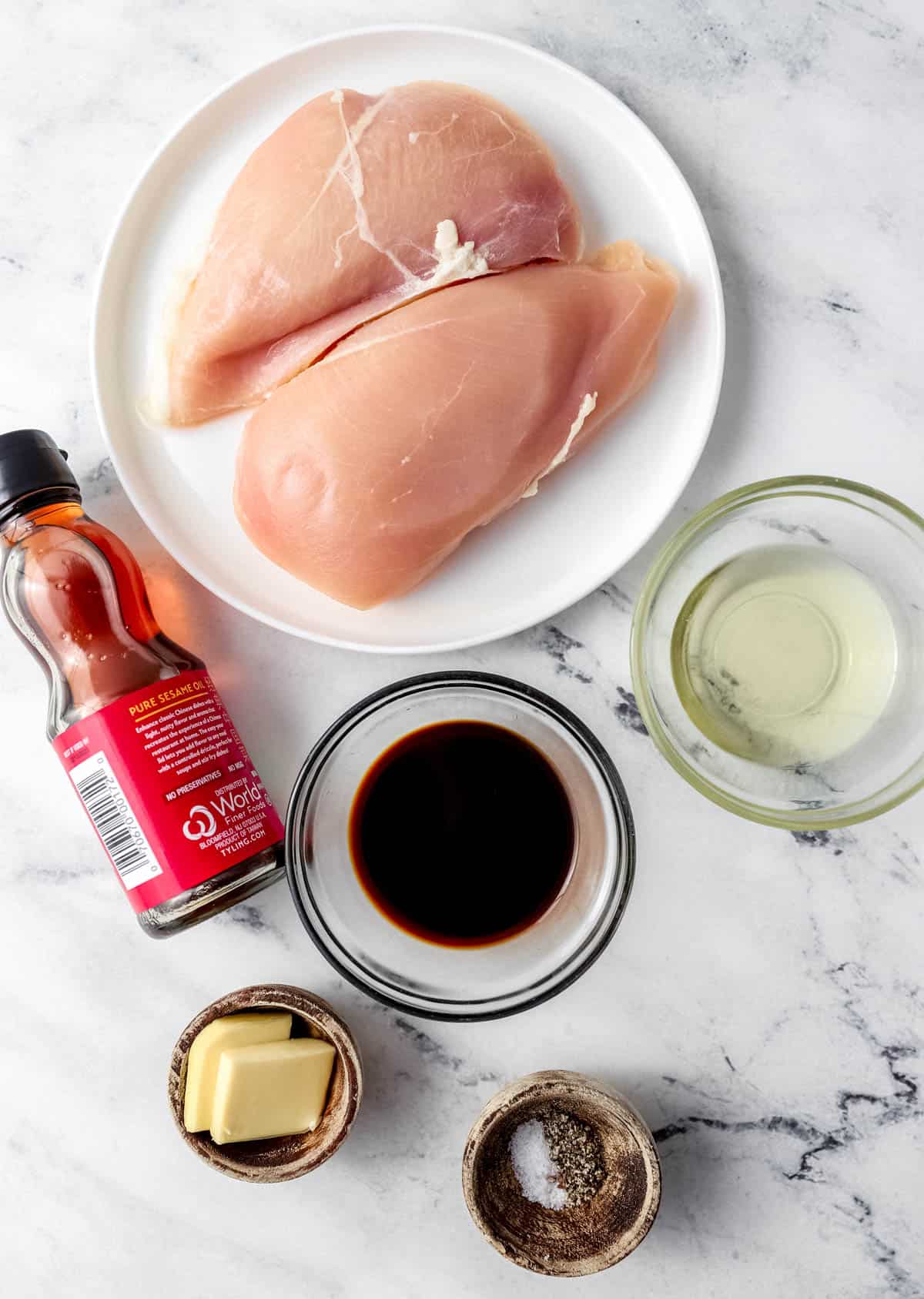 Overhead view of ingredients needed to make chicken in separate bowls and containers 