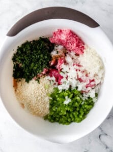 Meatloaf ingredients added to a large white mixing bowl.