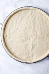 Overhead view of pizza dough on pan.