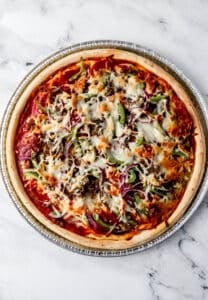 Overhead view of baked pizza on marble surface.