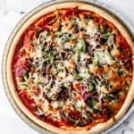 Finished pizza in pan on marble surface.