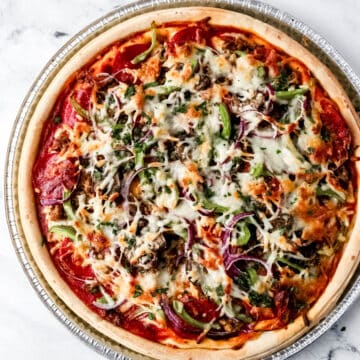 Finished pizza in pan on marble surface.