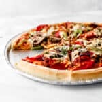 Close up size view of finished whole pizza with a slice taken out of it.