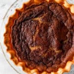 Overhead view of pie in glass pie plate on marble surface.