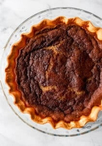 Overhead view of pie in glass pie plate on marble surface.