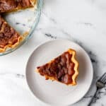 Overhead view of slice on pie on plate with the rest of the pie in the background.