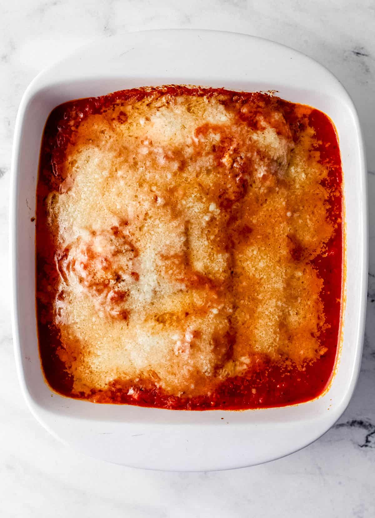 Overhead view of chicken topped with parmesan after baking for a few minutes. 