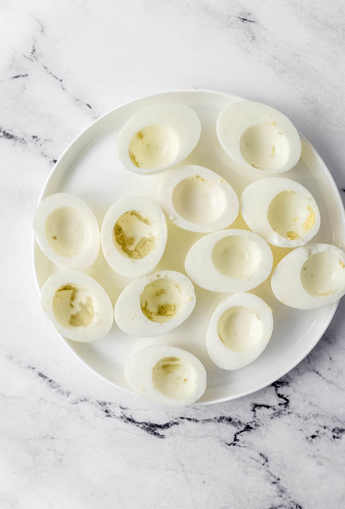 Hard boiled egg whites with yolk removed on white plate. 