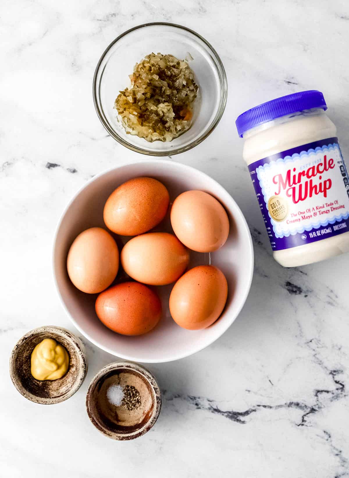 Ingredients needed to make deviled eggs in separate bowls and containers. 