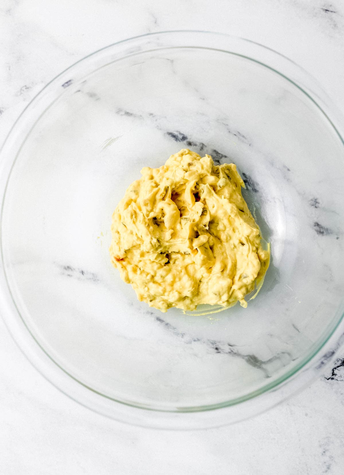 Deviled egg filling ingredients combined in large glass bowl. 